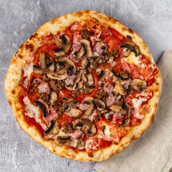 Pacioni's Pizzeria's Italian pizza with mushrooms, ham, and ground meat on a concrete background.