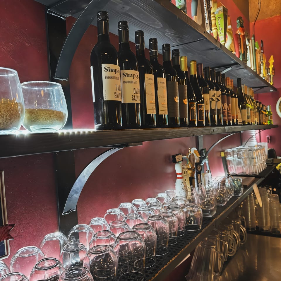 Wine bottles and beer taps on shelves above rows of clean glasses at Pacioni's Pizzeria bar.