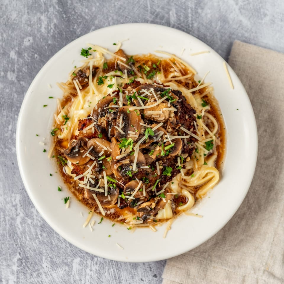 Pacioni's Pizzeria's Chicken Marsala, featuring chicken, mushrooms, and pasta, topped with parmesan and parsley.